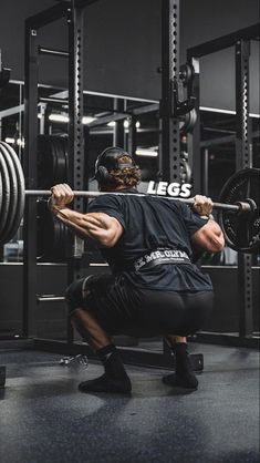 a man squats down while holding a barbell