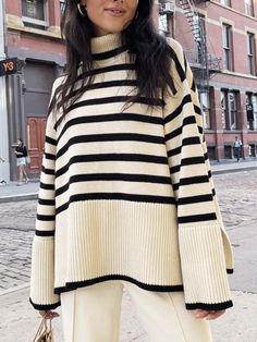 a woman standing on the street wearing a striped sweater