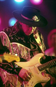 a man with a hat and fringe on playing an electric guitar