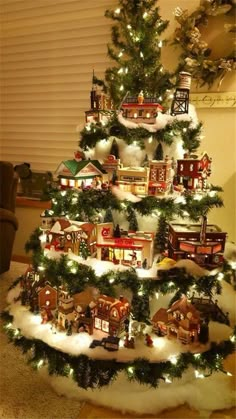 a christmas tree is decorated with miniature houses and lights