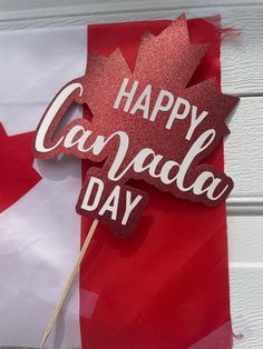 a canadian flag with a happy canada day sign on it and a maple leaf shaped cake topper