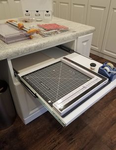 a kitchen counter with cutting mat and scissors on it next to the drawer that is open