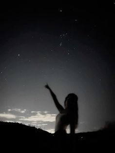 a woman standing on top of a hill under a sky filled with stars