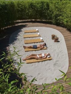 two women laying on lounge chairs in the sand