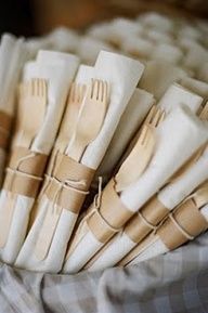 there are many forks and spoons in the basket on the tableclothes, ready to be eaten