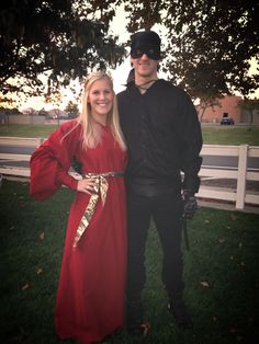 a man and woman dressed up in costume standing next to each other on the grass