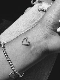 a woman's arm with a small heart tattoo on the left side of her wrist