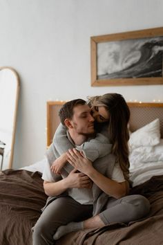 a man and woman cuddling on top of each other in the middle of a bed