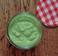 a glass jar filled with green liquid sitting on top of a wooden table next to a red and white checkered plate