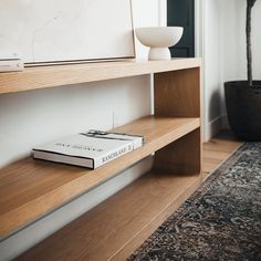 a bookshelf with a book on top of it next to a potted plant