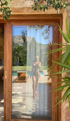 a woman in a bathing suit is reflected in the glass door of a pool area