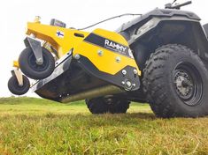 a yellow four - wheeler parked on top of a lush green field