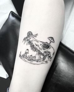 a black and white photo of a skull with mushrooms on it's head tattoo