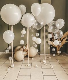 balloons and streamers are on the floor in front of a vase with dried grass