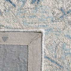 the corner of a rug with blue and white flowers on it's side,