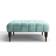 an ottoman with wooden legs and a blue velvet upholstered