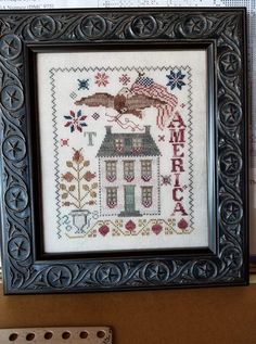 a framed cross stitch with an american flag on it