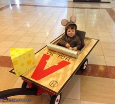 a baby in a mouse costume sitting in a wagon made out of cardboard and paper