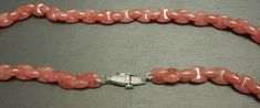 "With a total of approximately 228.00 carats of Genuine Earth-Mined Art Deco Shaped Interlocking Natural Watermelon / Coral Colored Rhodochrosite Gemstone beads with a Hand Engraved Platinum clasp Stamped: PT900 Necklace measuring approximately 16.25\" in length Weighing 45.7 grams Additional photos/details upon request. *Sale of necklace includes an appraisal certificate for your insurance purposes. All pieces shipped insured via USPS Priority Mail requiring signature upon delivery. Specialty g Luxury Oval Gemstone Beads Jewelry, Sunstone Gemstone Jewelry For Jewelry Making, Sunstone Gemstone For Jewelry Making, Round Sunstone Jewelry With Gemstone Beads, Elegant Round Sunstone Jewelry, Elegant Sunstone Jewelry, Round Shape, Sunstone Jewelry With Round Natural Stones, Elegant Sunstone Jewelry With Natural Stones, Art Deco Shapes