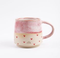 a pink and white coffee mug with hearts on the inside, sitting against a white background