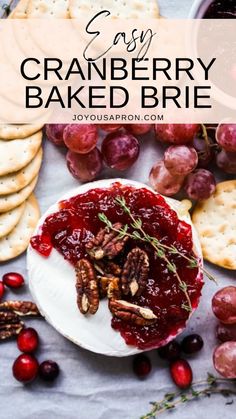 cranberry baked brie on a white plate surrounded by crackers and grapes