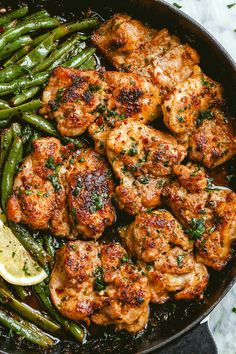 chicken and asparagus in a skillet with lemon wedges