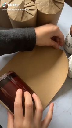 someone is making something out of cardboard and wrapping it in brown paper with their hands