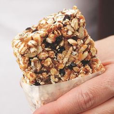 a hand holding a piece of granola and raisins on top of it