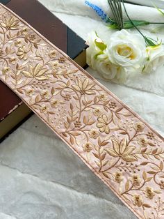 a close up of a ribbon on a table with flowers in the background and an open book