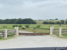 a gated entrance to a grassy field with trees in the background