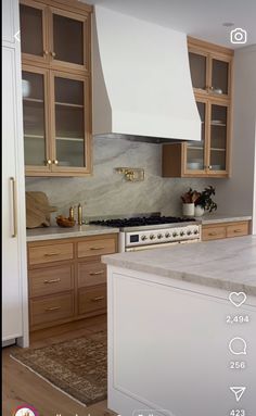 a kitchen with wooden cabinets and white marble counter tops, an oven hood over the stove