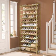 a gold shoe rack filled with pairs of shoes next to a stair case in a room