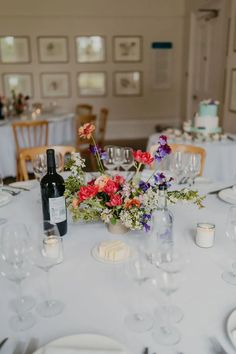 the table is set with wine glasses, plates and vases filled with colorful flowers