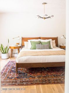 a bedroom with a bed, rug and lamp hanging from the ceiling in front of it