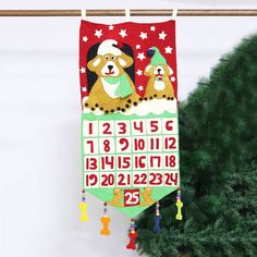 a calendar hanging on a wall next to a christmas tree with decorations and a dog