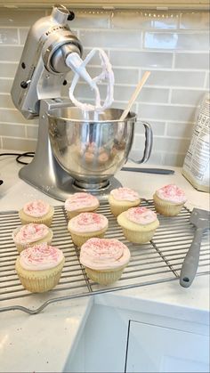 cupcakes cooling on the rack in front of a mixer with orange sprinkles