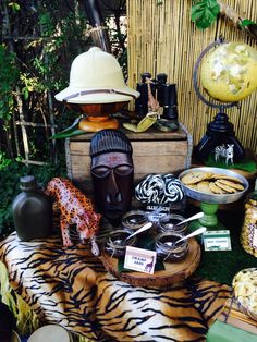 a table topped with lots of different items on top of a grass covered field next to a bamboo fence