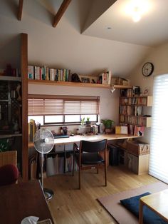 a living room filled with furniture and bookshelves next to a window covered in blinds