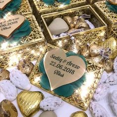 a table topped with lots of gold and white candies next to boxes filled with chocolates