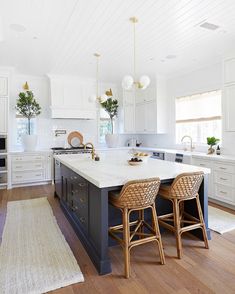 a kitchen with two stools in front of an island and white cabinets on the wall