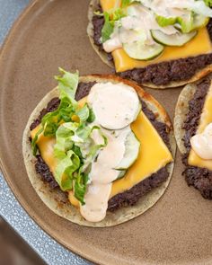 three burgers with cheese and lettuce on them are sitting on a plate