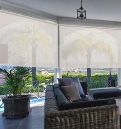 a living room filled with furniture and large windows covered in white blinds overlooking the ocean