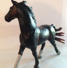 a toy horse that is standing up on a white surface with it's legs spread out