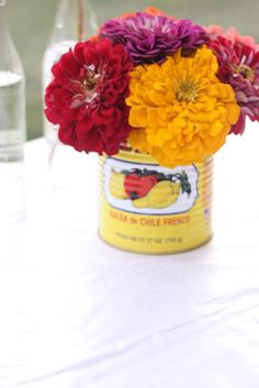 a can filled with flowers sitting on top of a table