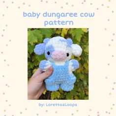 a hand holding a blue and white crocheted stuffed animal with the words baby dunggaree cow pattern on it