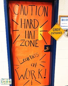 an orange door with writing on it that says caution hard hat zone learning is at work