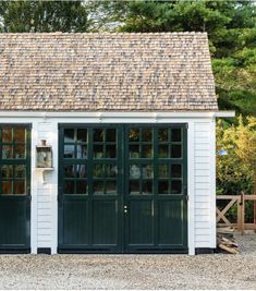 a white shed with green doors and windows