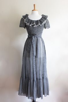 "Vintage 1960s/1970s maxi dress in black and white polka dot print sheer fabric with scoop neckline, fitted bodice, smocked detail along front bodice, overly ruffled trim along neckline, short puff sleeves, waist seam, matching sash belt that can be worn multiple ways, full gathered maxi length skirt, gathered ruffle panel along hem, and back zipper. Dress is quite sheer - best worn with slip if that is not desired look. Good vintage condition. full garment measurements: bust: 32\" - 35\" waist: Fitted Polka Dot Ruffled Maxi Dress, Fitted Polka Dot Maxi Dress With Ruffles, Fitted Swiss Dot Tiered Dress, Fitted Retro Swiss Dot Dress, Retro Fitted Swiss Dot Dress, Retro Swiss Dot Dress, Dots Fashion, Black Ruffle Dress, Polka Dots Fashion