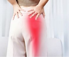 a woman with her hands on the back of her pants and holding her lower body in pain