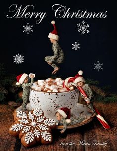 a christmas card with two elfs in a teacup and snowflakes on the table